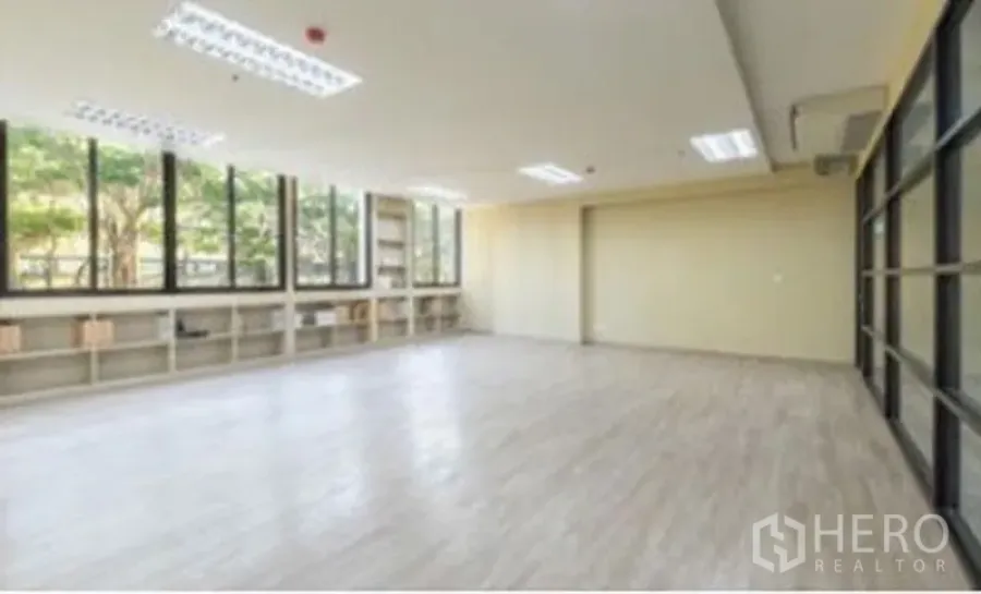 办公空间 出租在Chatuchak, Bangkok - 宽敞办公区，大面积窗户与低矮置物架，木纹地面，顶灯与玻璃隔断。