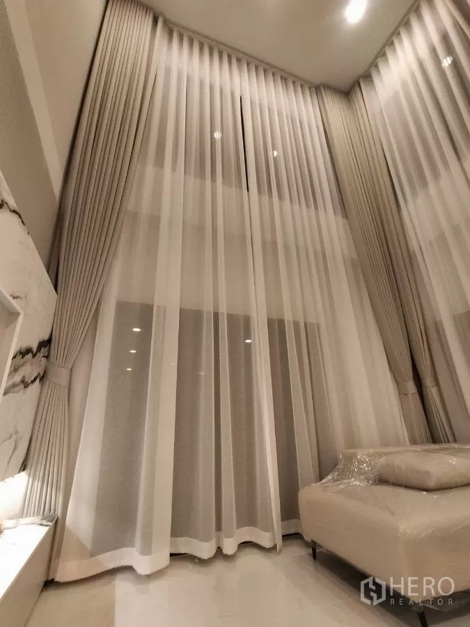 Detached House for rent in Bang Phli, Samut Prakan - Close-up of tall sheer curtains under the high ceiling in the living area.