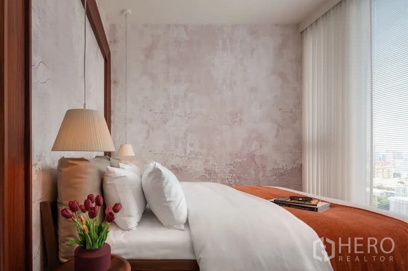 Condominium for sale in Watthana, Bangkok - Cozy bedroom with textured feature wall, corner windows and tulip bedside decor.