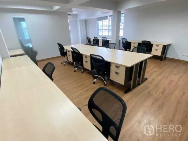 Office Space for rent in Khlong Toei, Bangkok - Bright office floor with two rows of desks, large windows for natural light, and wood-look floors.