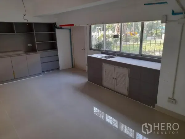 零售空间 出租在Ratchathewi, Bangkok - 后场茶水间，带水槽、储物柜与宽窗，可见室外绿化。