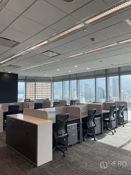 Office Space for rent in Dusit, Bangkok - Bright workstation rows beside expansive glazing with a Bangkok skyline backdrop.
