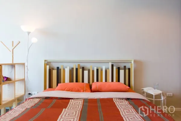 公寓 出租在Watthana, Bangkok - 温馨卧室，现代几何造型床头板，床头柜与落地灯，暖色床品，位于瓦他那区公寓。