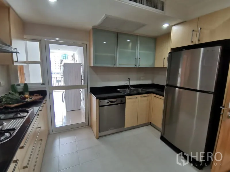 公寓 出租在Khlong Toei, Bangkok - 封闭式现代厨房，黑色台面，不锈钢冰箱、洗碗机、玻璃门吊柜，并通向家务阳台。