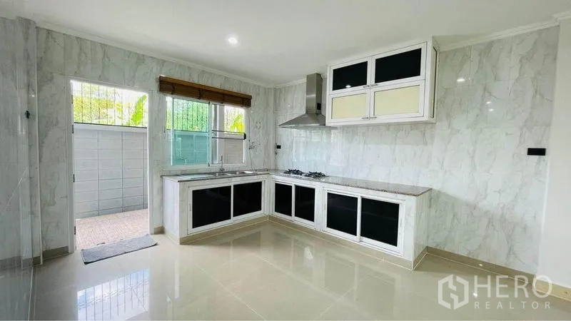 Detached House for rent in Bang Kapi, Bangkok - Modern L-shaped kitchen with gas hob, hood, upper cabinets and a door to the backyard.