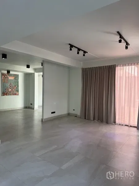 Home Office for rent in Watthana, Bangkok - Open-plan living area with track lighting, gray curtains and light tiles.