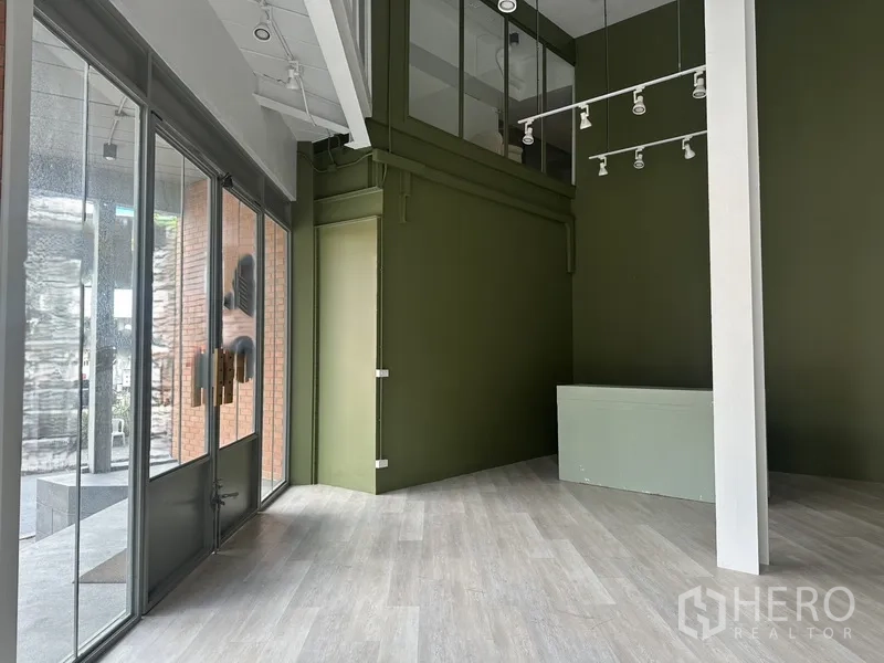 零售空间 出租在Khlong Toei, Bangkok - 靠入口的区域，玻璃门、绿墙与吊轨射灯。