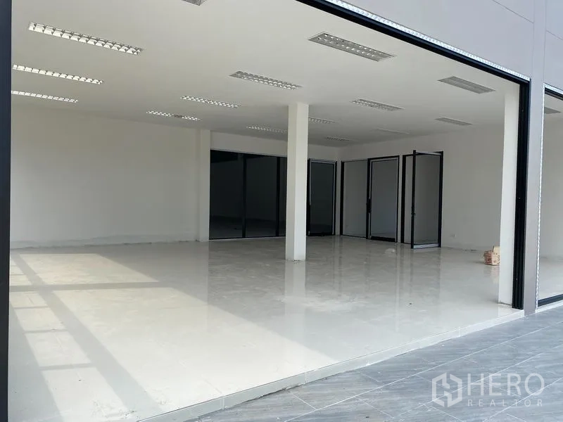Warehouse for rent or sale in Bang Len, Nakhon Pathom - Glass-fronted ground-floor office or showroom with bright white tiled flooring and ceiling lights.