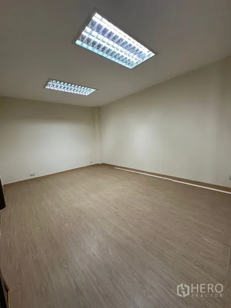 Warehouse for rent in Suan Luang, Bangkok - Compact office room with wood-look flooring and fluorescent ceiling lights.