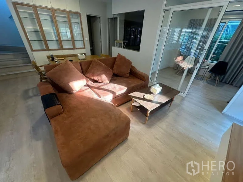 独立式住宅 出租在Prawet, Bangkok - 温馨客厅，L 型沙发，连接玻璃隔断的多功能房。