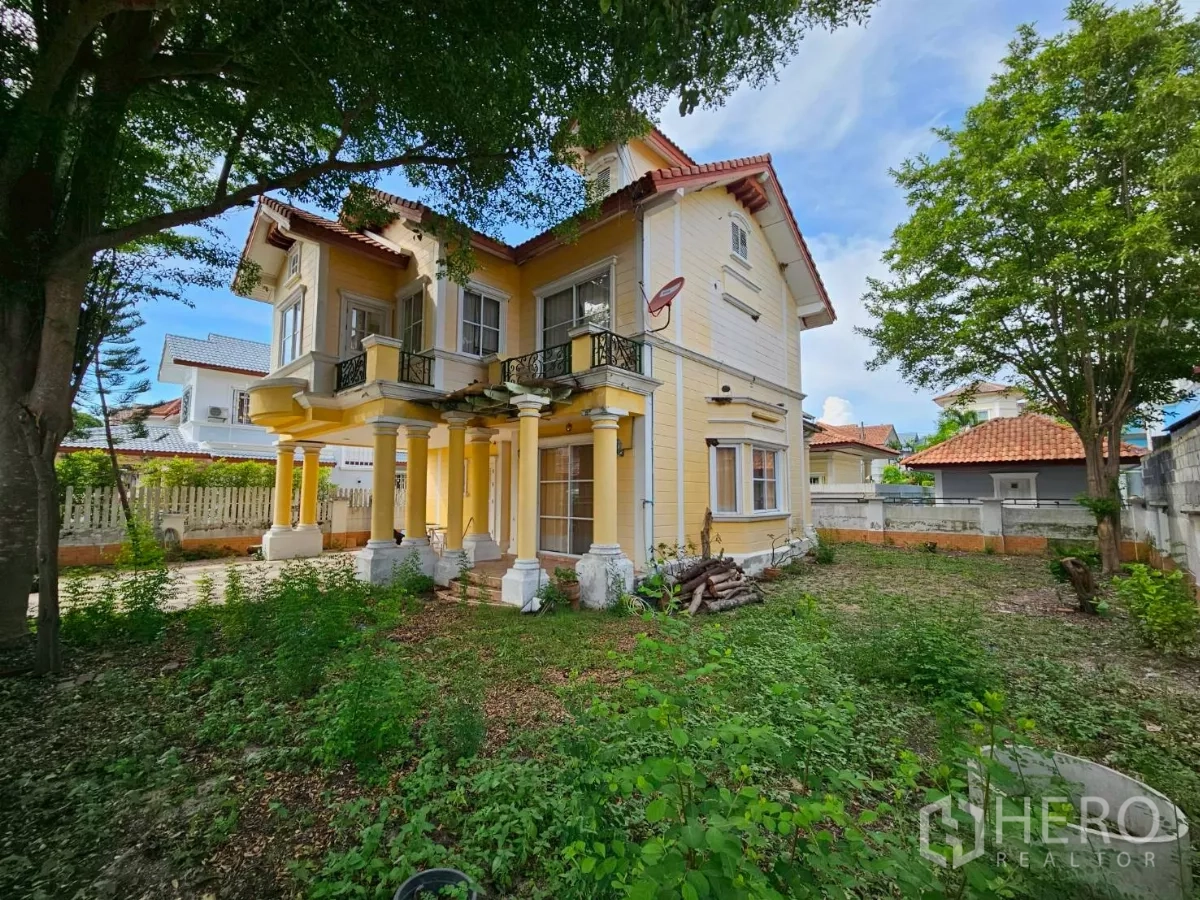 Detached House for rent or sale in Bang Lamung, Chon Buri - Corner angle showing wraparound garden, balconies, and classical columns of the house.