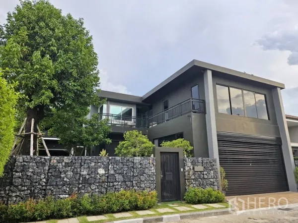 Detached House for sale in Thawi Watthana, Bangkok - Modern two-storey detached house with dark facade, large windows and a stone boundary wall in Thawi Watthana.
