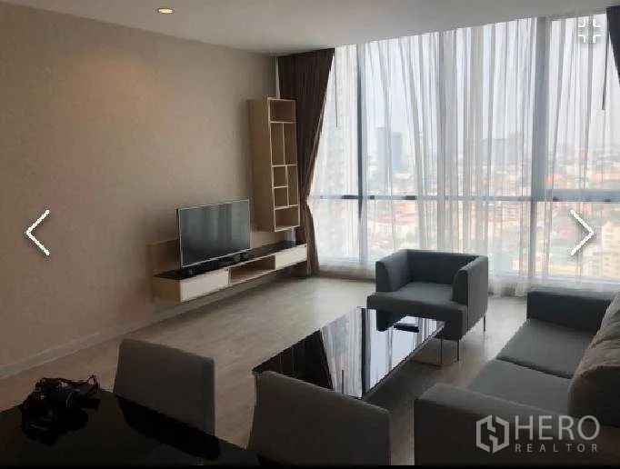 公寓 出租在Watthana, Bangkok - 客厅配沙发与电视柜，落地窗俯瞰曼谷天际线