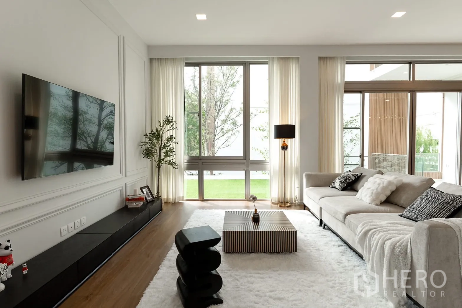 Detached House for rent in Saphan Sung, Bangkok - Bright living room with floor-to-ceiling windows, L-shaped sofa and wall-mounted TV