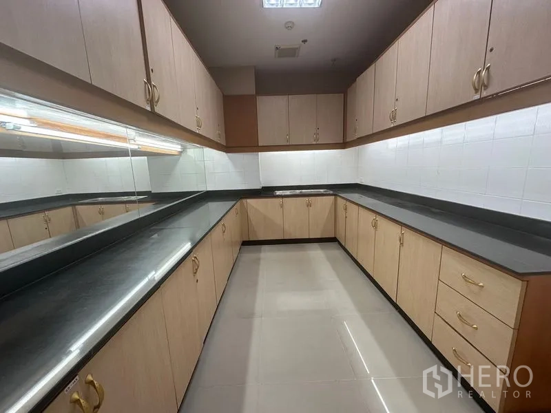 Office Space for rent in Suan Luang, Bangkok - Office pantry with U-shaped countertops, light wood cabinetry and mirrored backsplash.