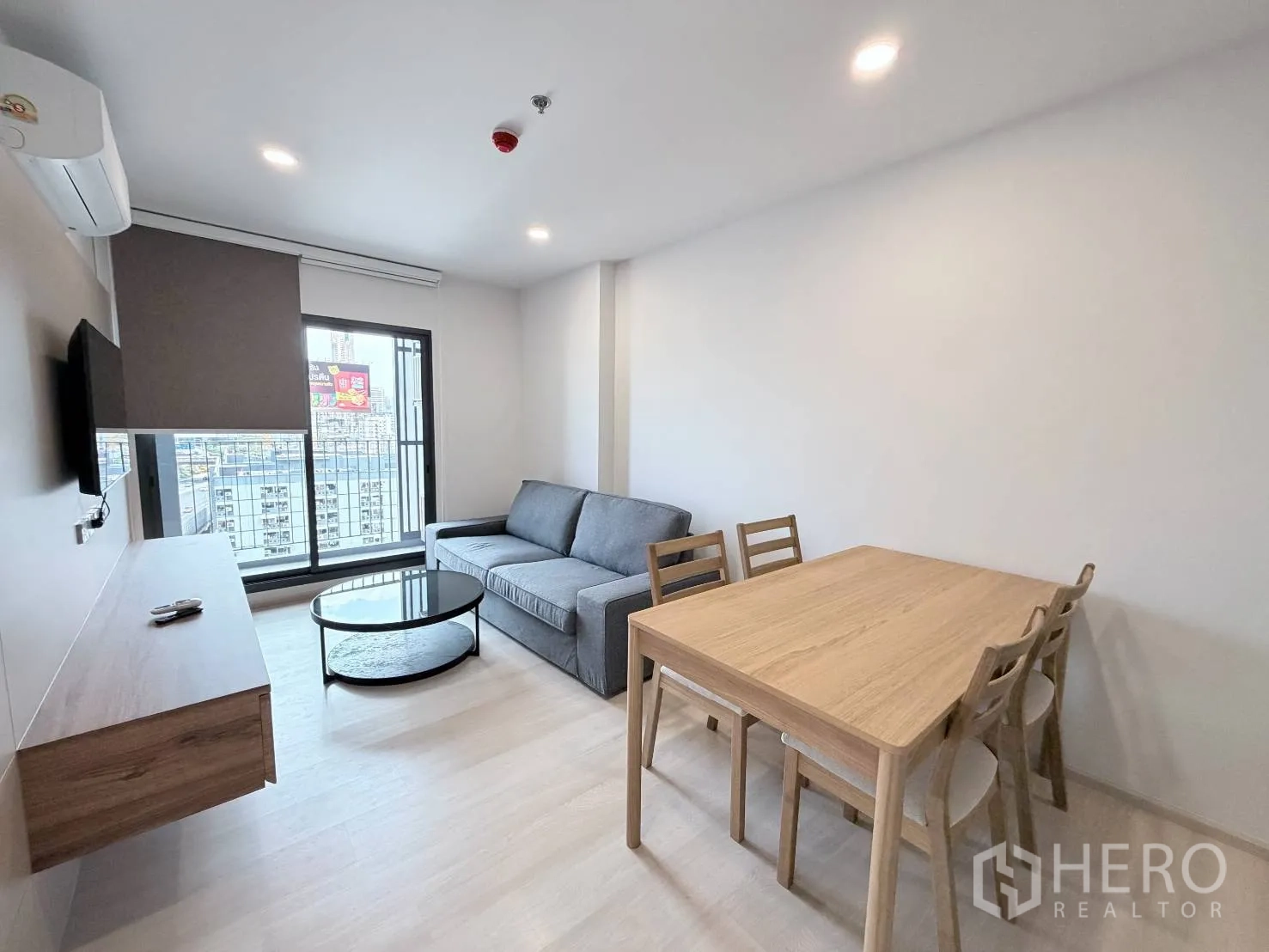 คอนโด for rent in Din Daeng, Bangkok - ห้องนั่งเล่นและรับประทานอาหารมีโซฟาสีเทา โต๊ะกลางทรงกลม ชุดโต๊ะอาหาร และประตูออกระเบียง