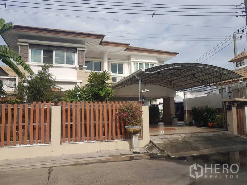 Detached House for sale in Suan Luang, Bangkok - Front exterior of two-storey detached home with gated fence and large covered carport.