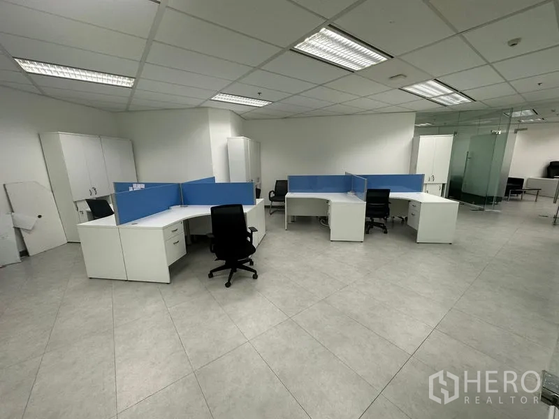 Office Space for rent - Open-plan workspace with blue-partition desks, swivel chairs and surrounding glass walls.