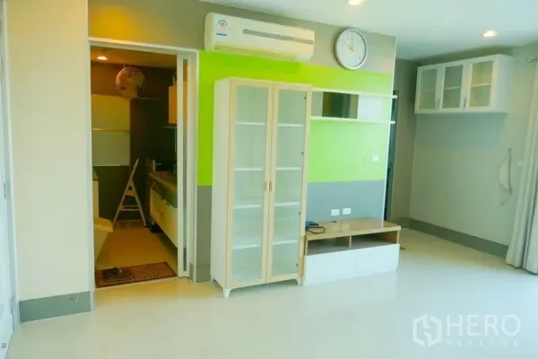 คอนโด ให้เช่าหรือขายในKhlong San, Bangkok - ห้องนั่งเล่นสว่าง ผนังไฮไลต์สีเขียว ตู้โชว์กระจก และเครื่องปรับอากาศ