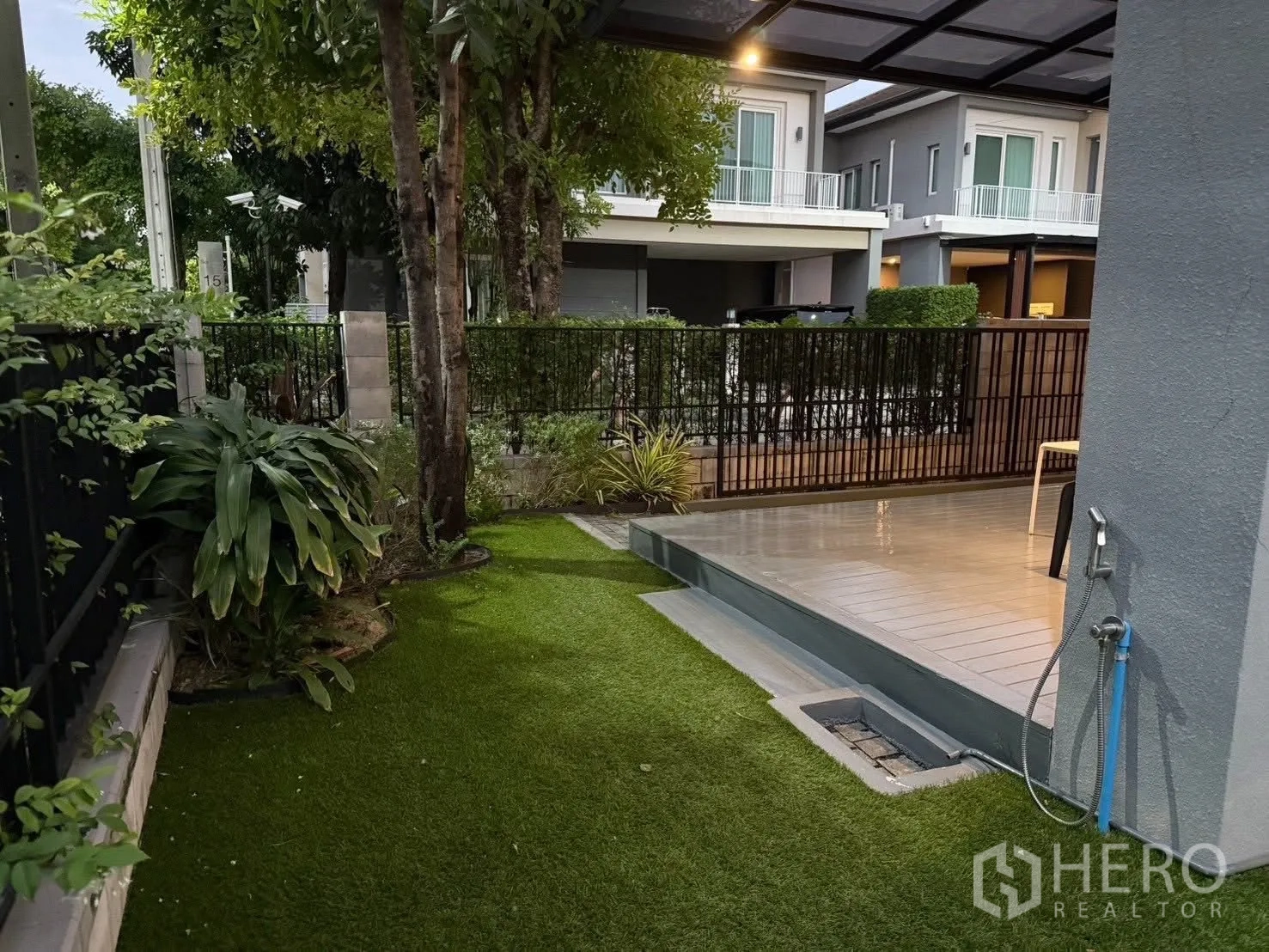 Detached House for rent in Bang Na, Bangkok - Small green garden with trees, plants, faucet and a fenced boundary next to the deck.