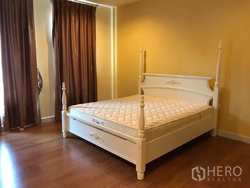 Townhouse for rent in Wang Thonglang, Bangkok - Master bedroom featuring a white four-poster bed, brown curtains and wood flooring.