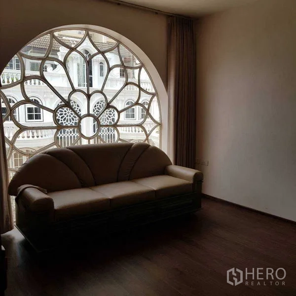 Home Office for rent in Watthana, Bangkok - Living room with large decorative rose window and sofa facing the street.