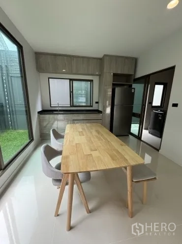 บ้าน ให้เช่าในBang Kapi, Bangkok - ครัวสว่างโปร่งพร้อมโต๊ะทานอาหารไม้ ชุดตู้ และวิวสวน