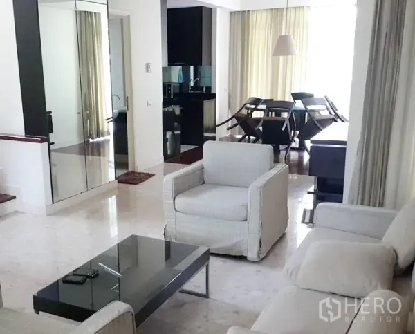 Detached House for rent in Wang Thonglang, Bangkok - Bright lounge with armchairs, glass coffee table and mirrored storage opening to dining area and kitchen.