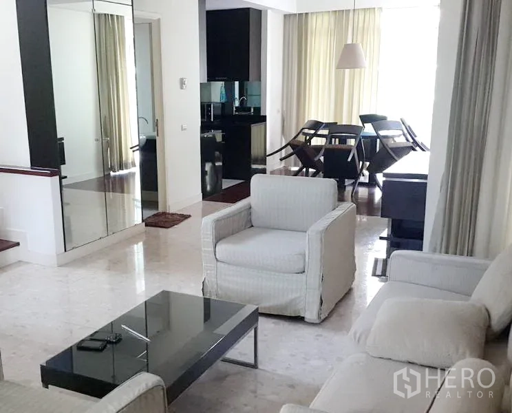 Detached House for rent in Wang Thonglang, Bangkok - Bright lounge with armchairs, glass coffee table and mirrored storage opening to dining area and kitchen.