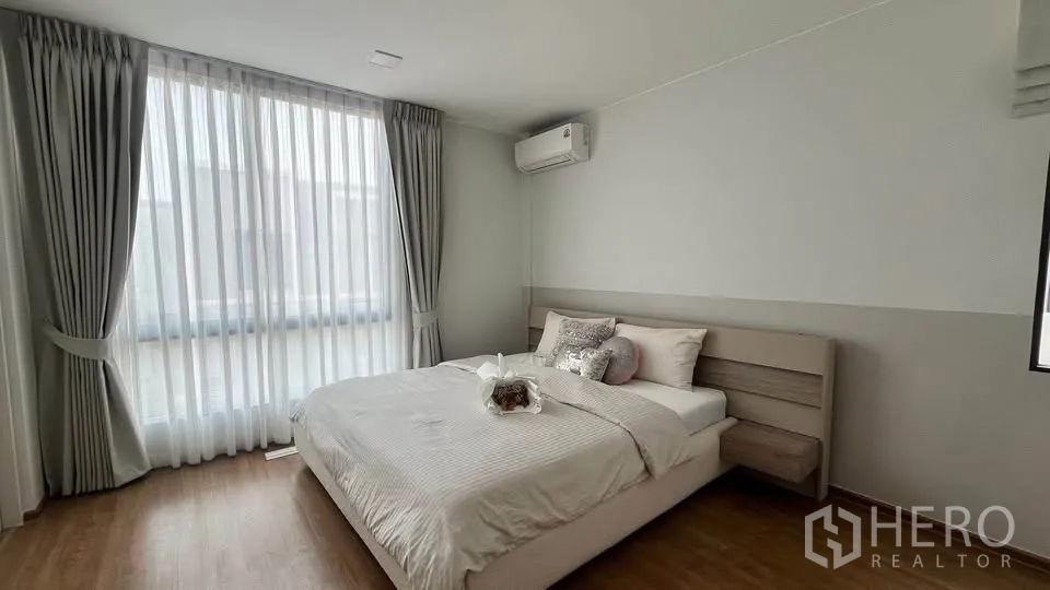 Townhouse for rent or sale in Bang Phli, Samut Prakan - Bright bedroom with large window, air conditioner and bed.