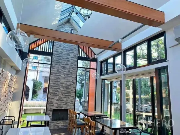 Retail Space for rent in Suan Luang, Bangkok - Double-height retail space with skylight, wood beams, floor-to-ceiling windows, and a brick feature wall.