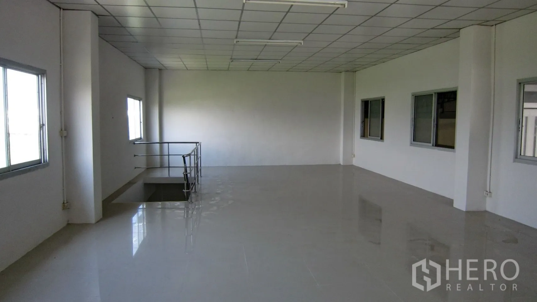 Warehouse for rent in Bang Sao Thong, Samut Prakan - Upper-level office space with windows and stairwell access inside the warehouse.