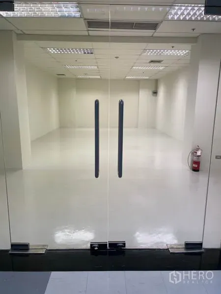 Office Space for rent in Khlong Toei, Bangkok - Glass double doors opening to a bright 55 sqm open-plan office with white floors and grid ceiling lights.