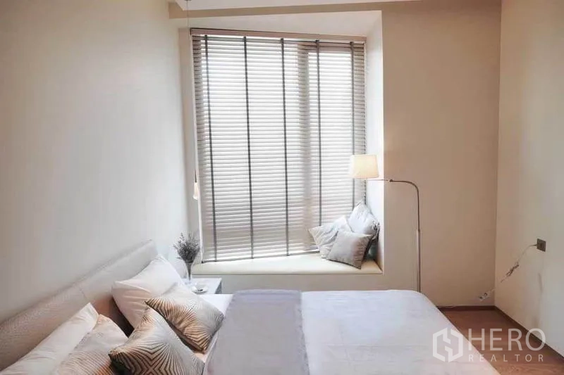 公寓 出租在Bang Rak, Bangkok - 卧室带窗边坐榻、百叶与落地灯。