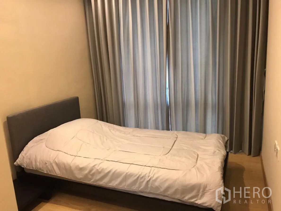 Condominium for rent in Watthana, Bangkok - Cozy second bedroom with single bed and floor-length curtains.