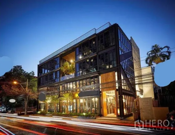 พื้นที่ขายปลีก ให้เช่าในWatthana, Bangkok - อาคารพาณิชย์สมัยใหม่กระจกทั้งหลังช่วงพลบค่ำ ไฟสว่างและจัดสวนด้านหน้า