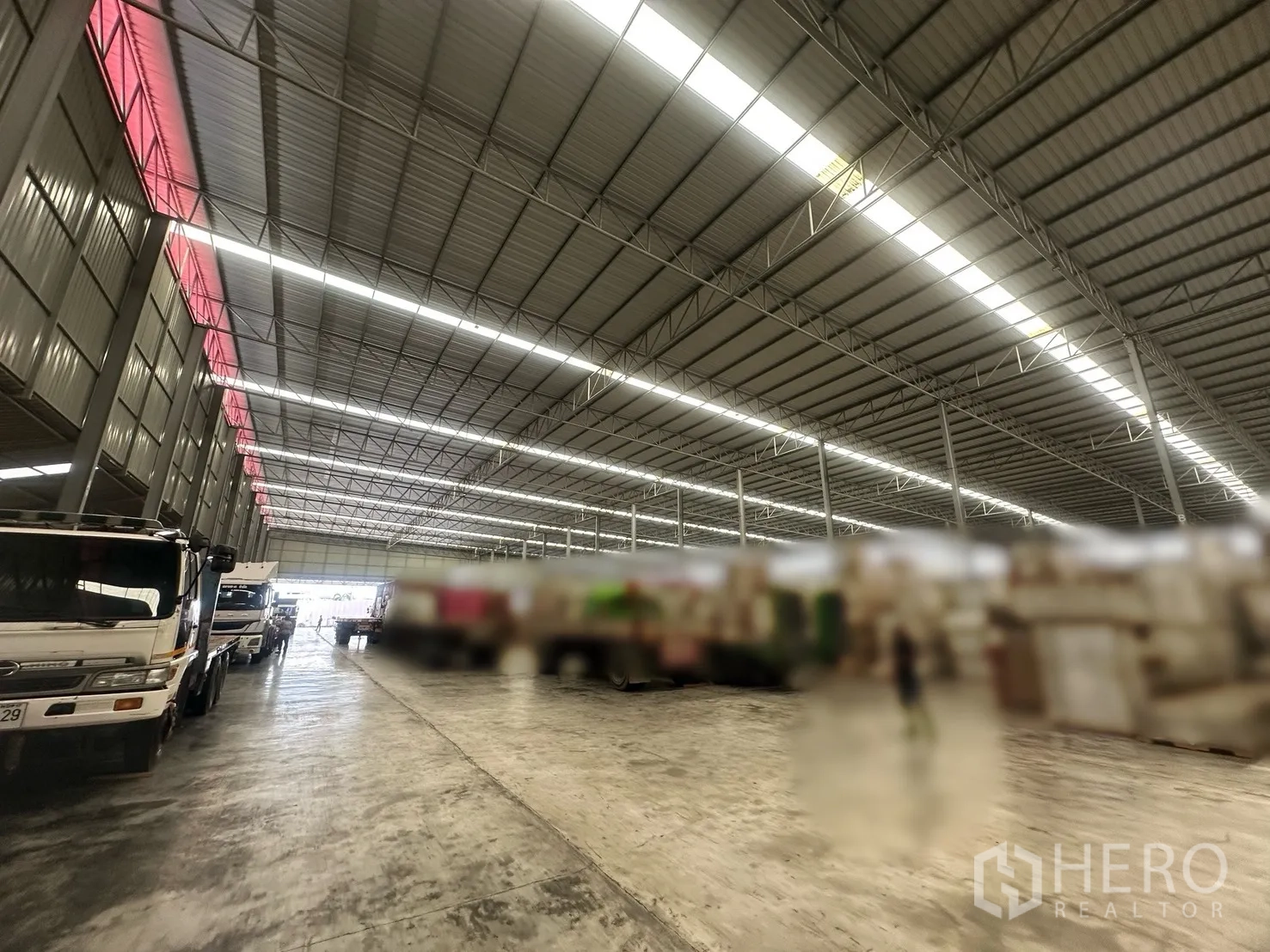 工厂 出租 - 仓库内装卸通道，卡车停靠在高棚灯下。
