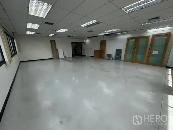 Office Space for rent in Khlong Toei, Bangkok - Bright office area showing multiple access doors, suspended ceiling and window blinds.