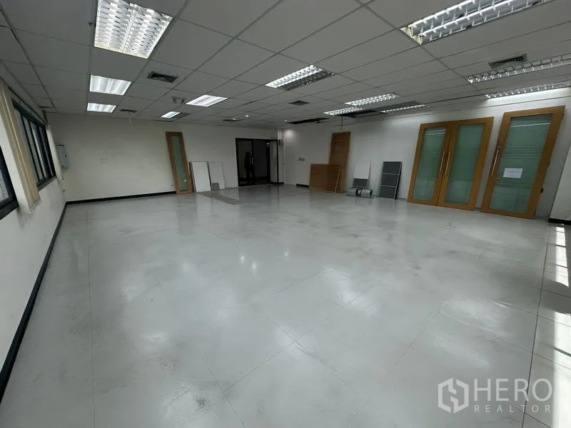 Office Space for rent in Khlong Toei, Bangkok - Bright office area showing multiple access doors, suspended ceiling and window blinds.
