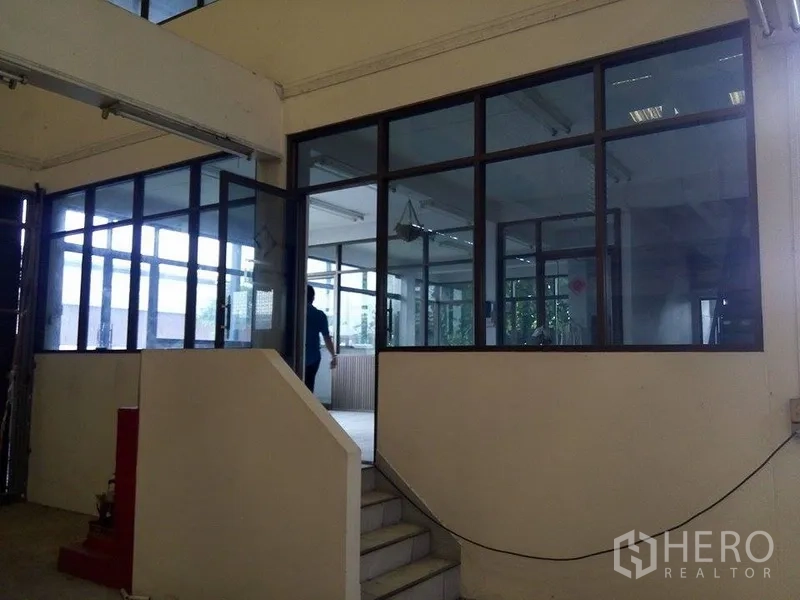 Warehouse for rent in Min Buri, Bangkok - Glass-partitioned elevated office inside the warehouse with stair access.