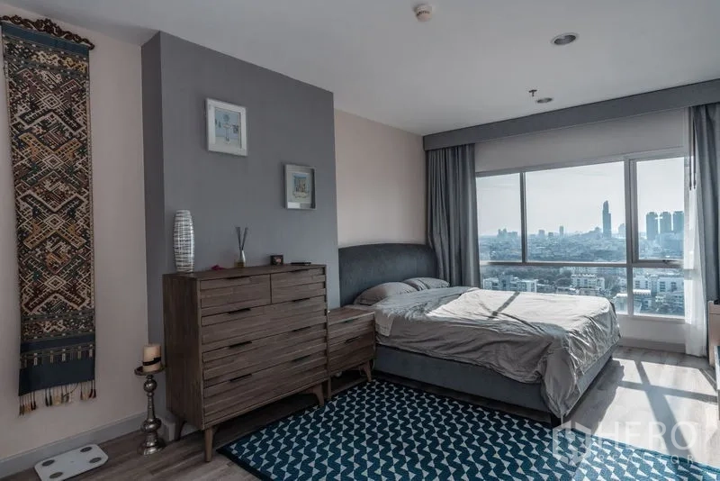Condominium for rent in Sathon, Bangkok - Master bedroom with large window, dresser, and panoramic Bangkok city view.