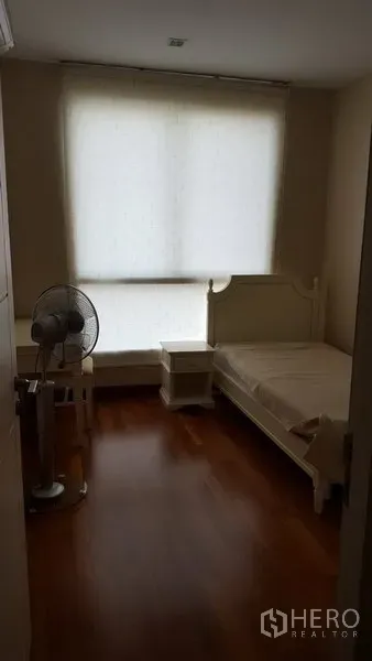 公寓 出租在Bang Rak, Bangkok - 次卧配单人床与床头柜，大窗遮光帘与木地板。