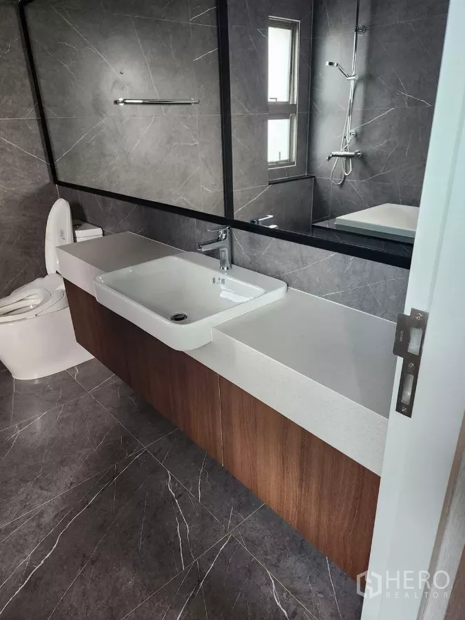 บ้าน ให้เช่าหรือขายในBueng Kum, Bangkok - ห้องน้ำเคาน์เตอร์ยาว กระจกเต็มผนัง และกระเบื้องโทนหินเข้ม