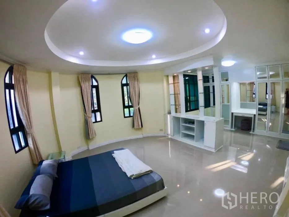 Townhouse for rent in Watthana, Bangkok - Corner bedroom with circular ceiling detail, arched windows, wardrobes and a vanity area.