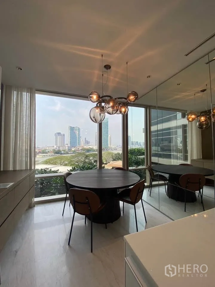 Condominium for rent in Sathon, Bangkok - Dining nook with modern chandelier, mirrored wall, and river outlook.