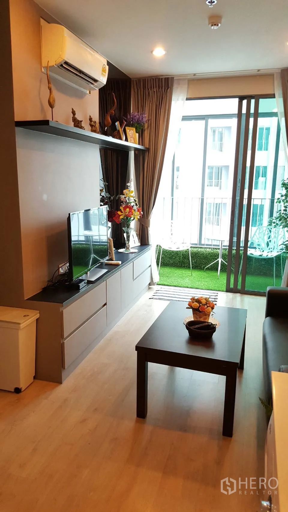 公寓 出租在Bang Rak, Bangkok - 木地板客厅连接绿色阳台与电视矮柜。