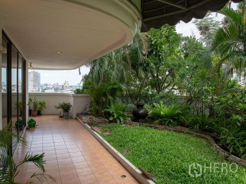 Apartment for rent in Khlong Toei, Bangkok - Covered terrace beside a private lawn and tropical garden with city views.