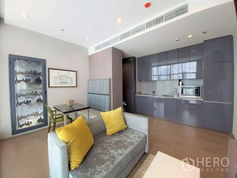 Condominium for sale in Bang Rak, Bangkok - Bright living–dining space beside a modern kitchenette, city-themed glass door, and comfortable seating.