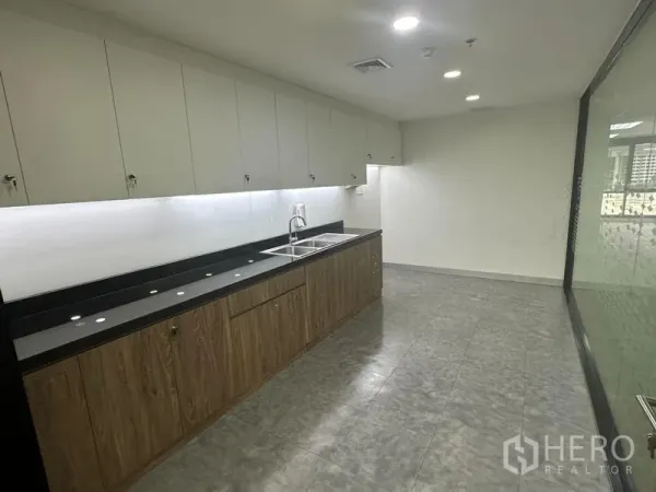 Office Space for rent in Khlong Toei, Bangkok - Office pantry with long countertop, sink, overhead cabinets and under-cabinet lighting.