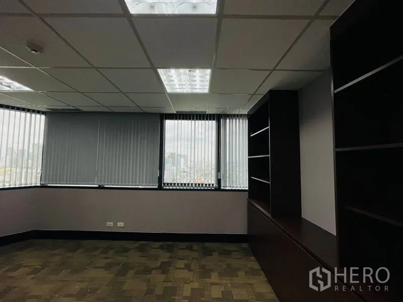Office Space for rent - Corner private office with city views, vertical blinds and built-in dark wood shelving.